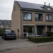 Duurzame Nederlandse woning met zonnepanelen en laadpaal in een woonstraat.